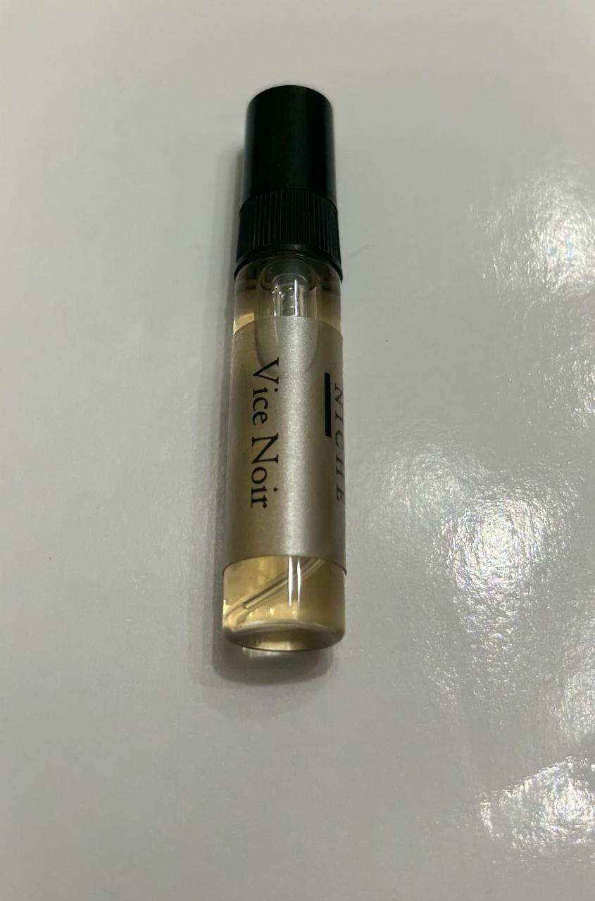 Vial labeled 'Vice Noir' on a reflective white surface